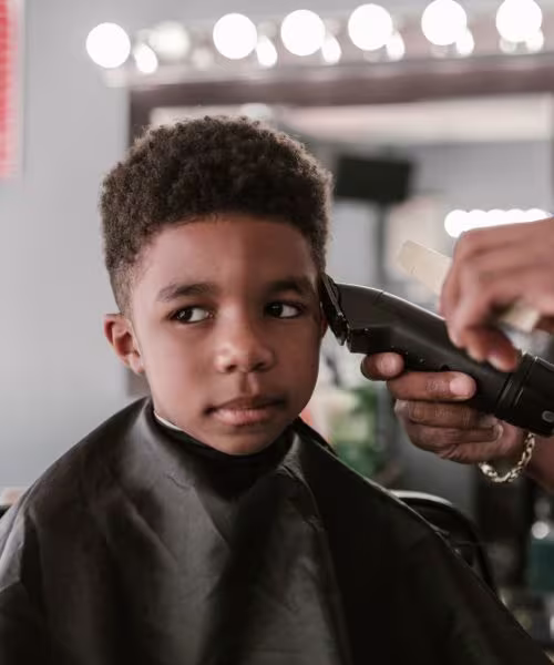 Criança feliz recebendo corte infantil especializado na Barbearia 87